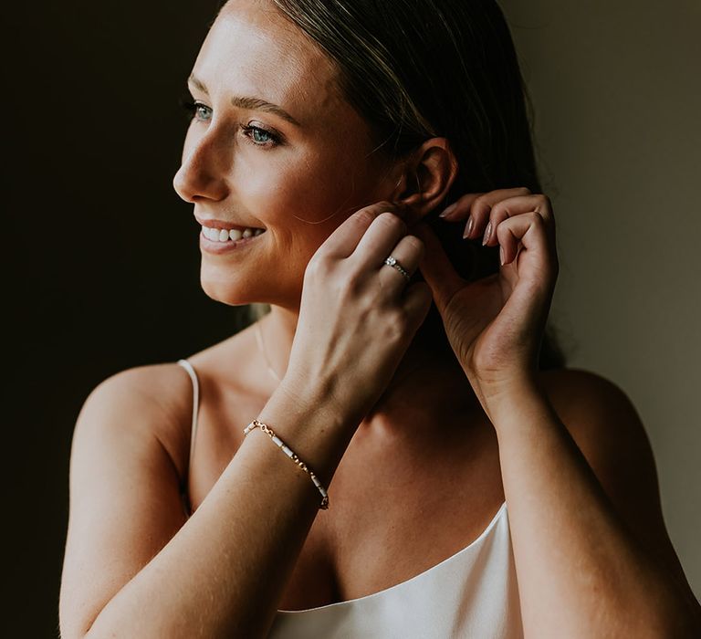 Bride puts in wedding earrings getting ready for the wedding 