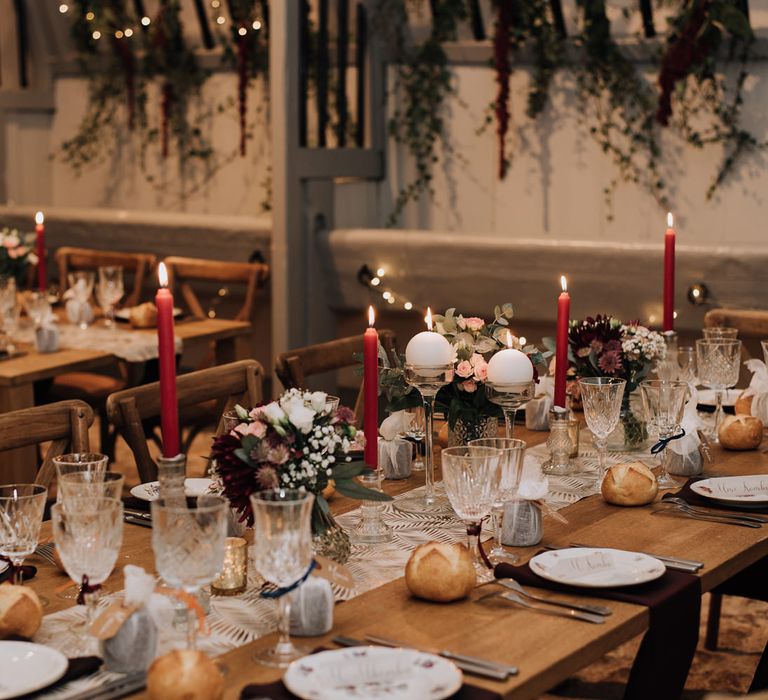 Romantic wedding reception with candles and burgundy flower centrepieces 