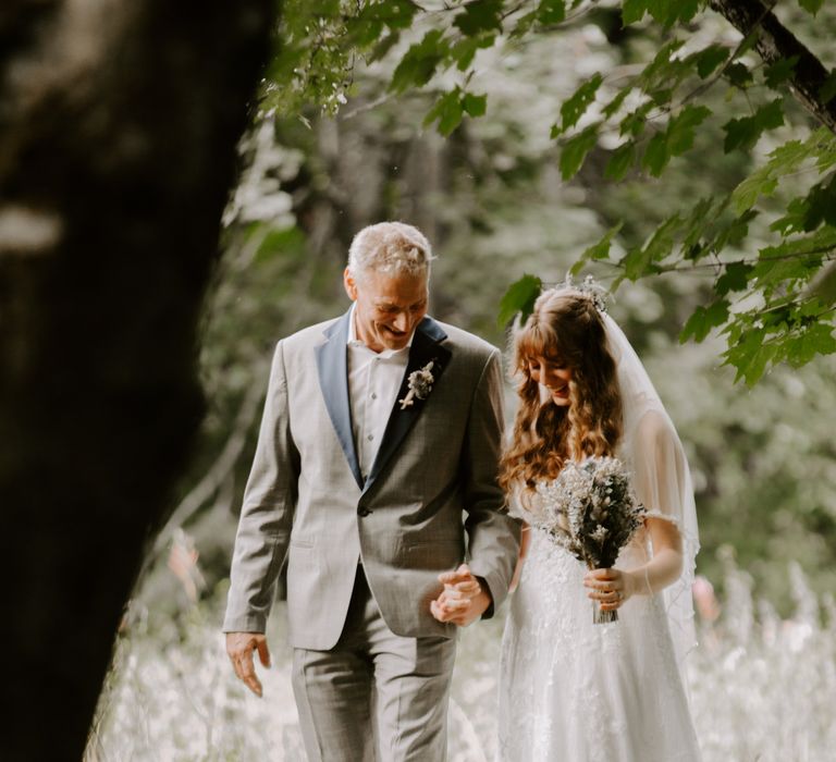 Father of the bride in light grey suit with the bride in sparkly wedding dress