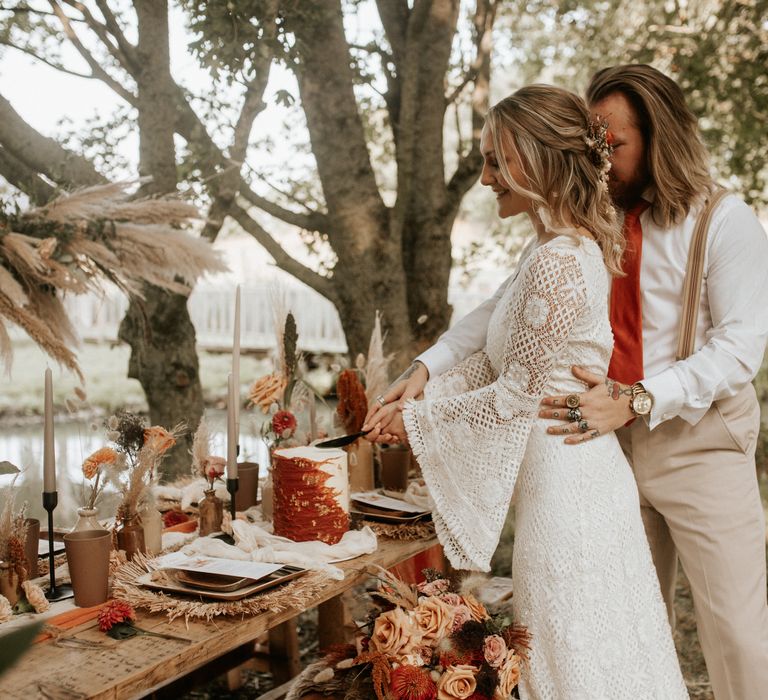 Bride & groom cutting wedding cake outdoors 