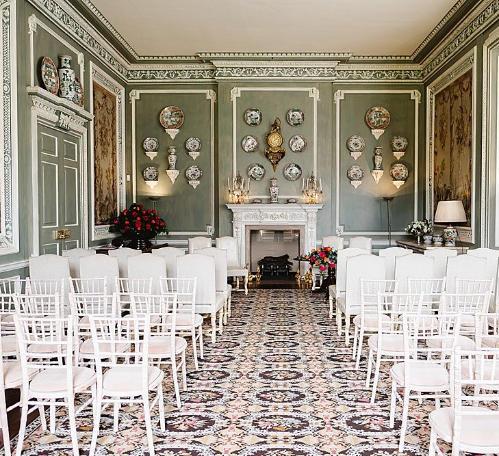 Ceremony room at Leeds castle with white chairs and plates on the wall 