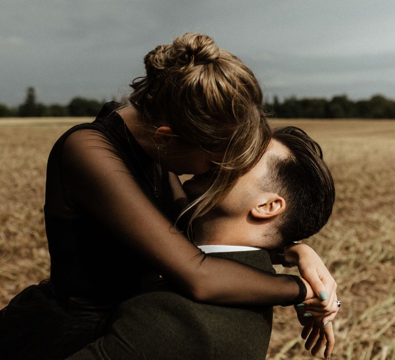 Bride & groom kiss in golden fields on wedding day