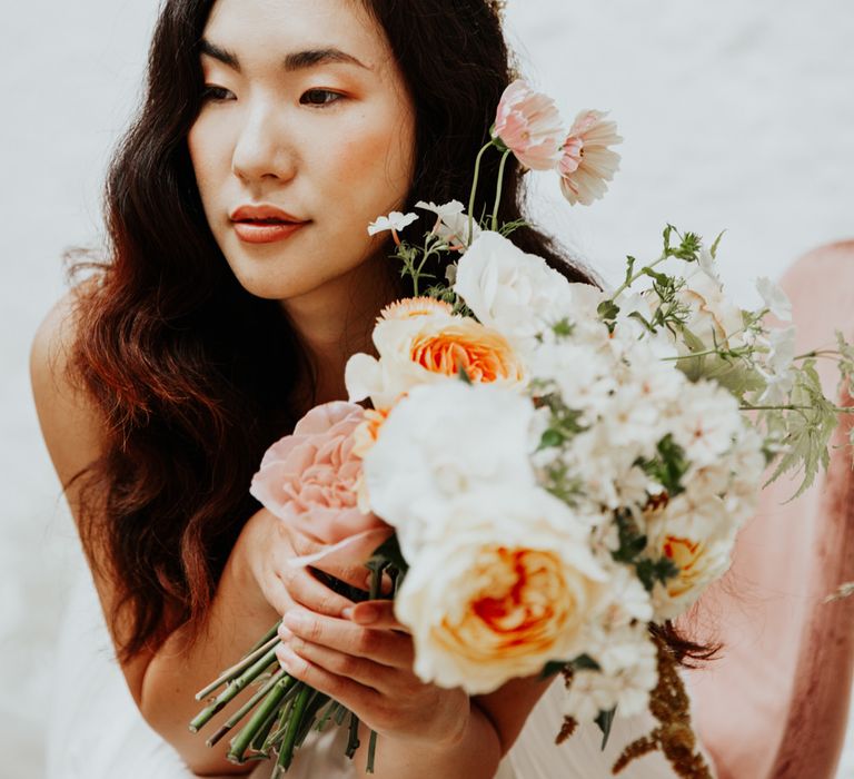 The bride holding a bouquet of orange and white flowers for an autumn wedding