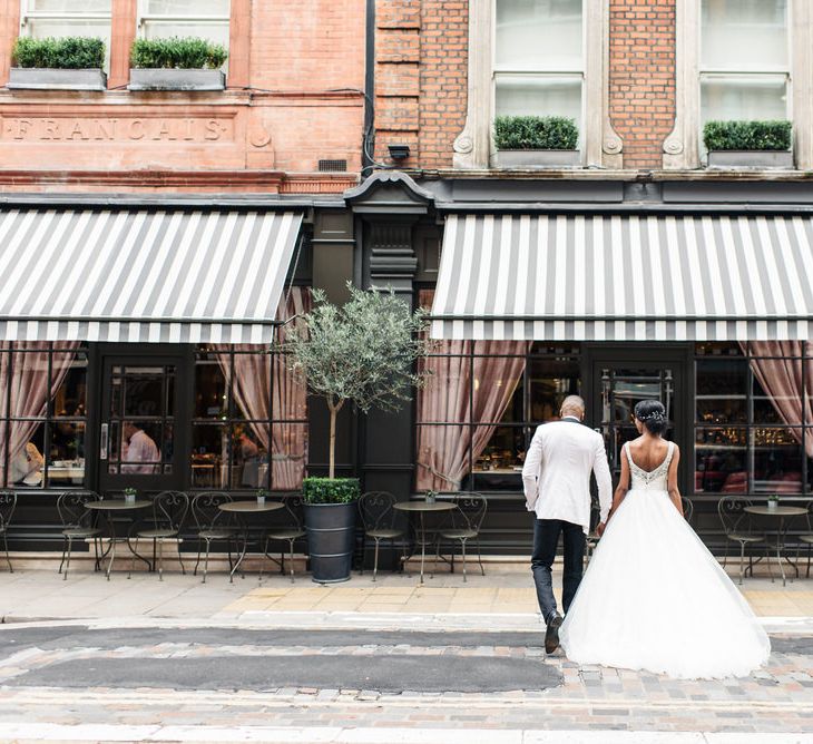 Bride & groom stand with their backs to the camera on the streets of London