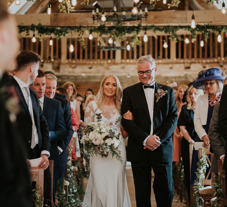 Bride in white Charlie Brear wedding dress and white Augusta Jones lace top walks down the aisle with father at Caswell House wedding