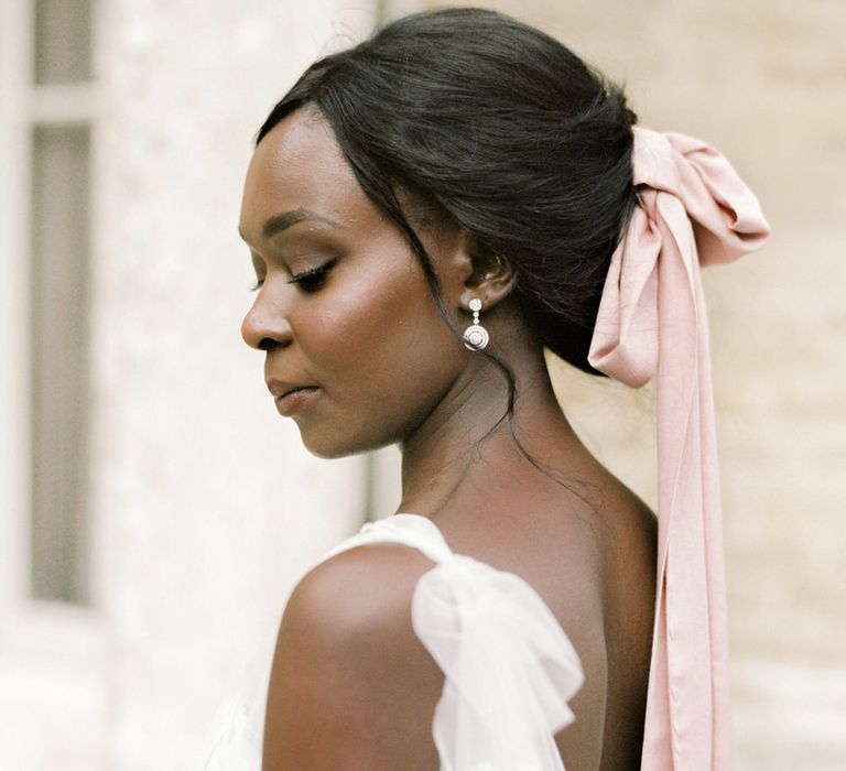 The bride wears a one shoulder tulle wedding dress by Anna Campbell, with pink silk ribbon in her hair