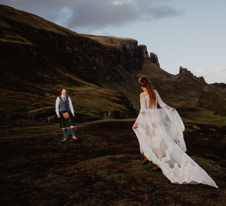 Bride walks along the hillside whilst wearing Watters lace gown