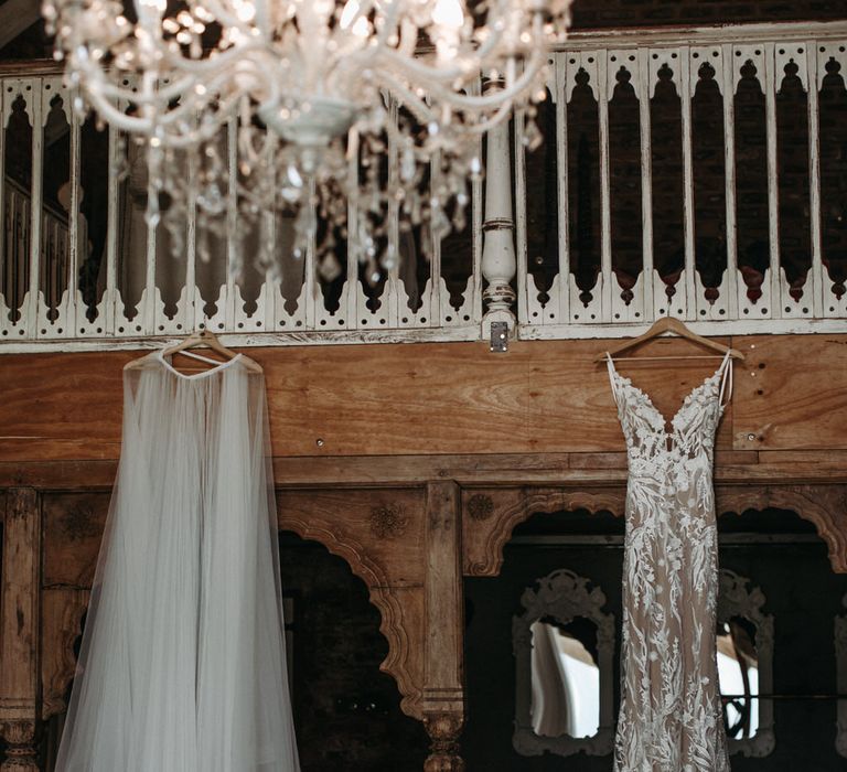 Lace embroidered wedding dress and tulle overskirt hanging up before the wedding