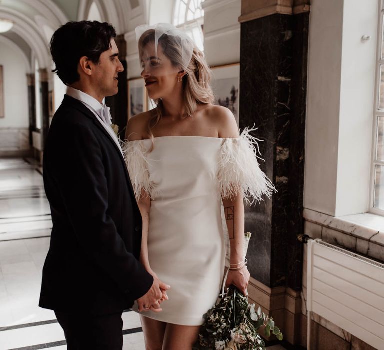 Bride looking into grooms eyes wearing off the shoulder wedding dress