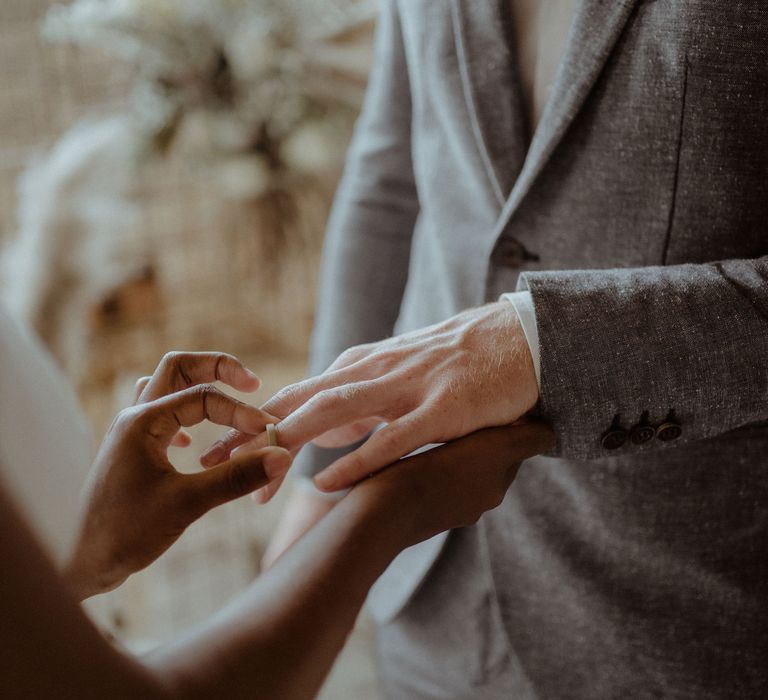 A bride places the ring on the grooms finger. 