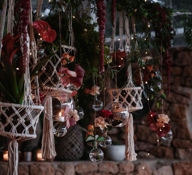 Romantic hanging red flowers and foliage with candles and macrame decor