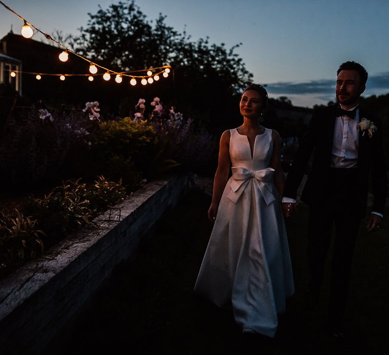 Bride & groom walk together as the night begins on their wedding day