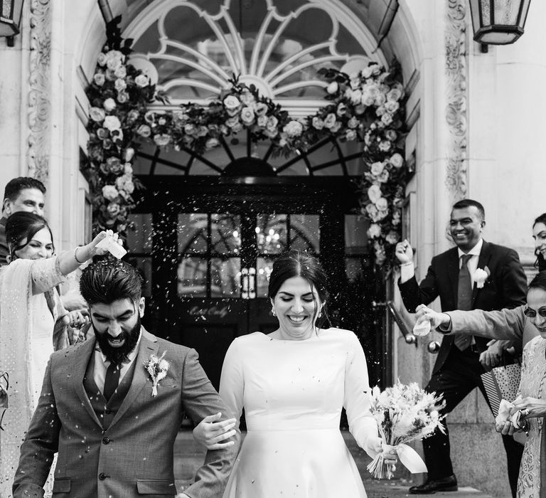 Bride & groom leave Chelsea Old Town Hall in black & white image on their wedding day