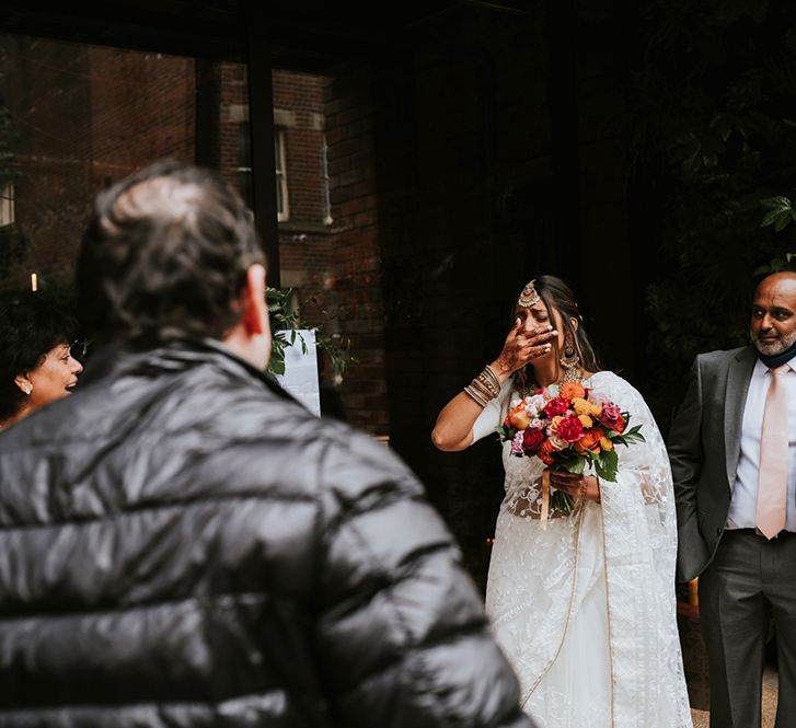 A bride is surprised outside her wedding venue by a family member who arrived just in time.