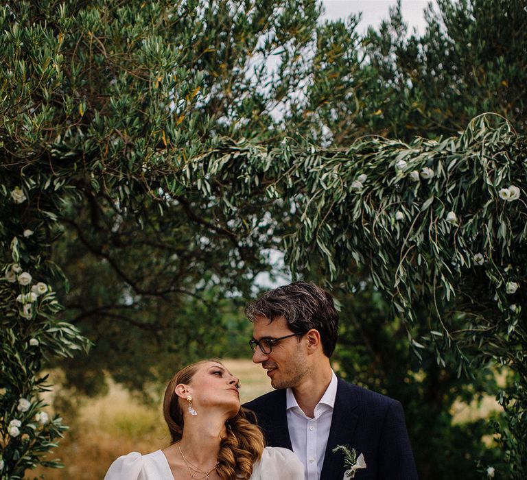 Bride & groom stand outdoors as they look lovingly at one another 