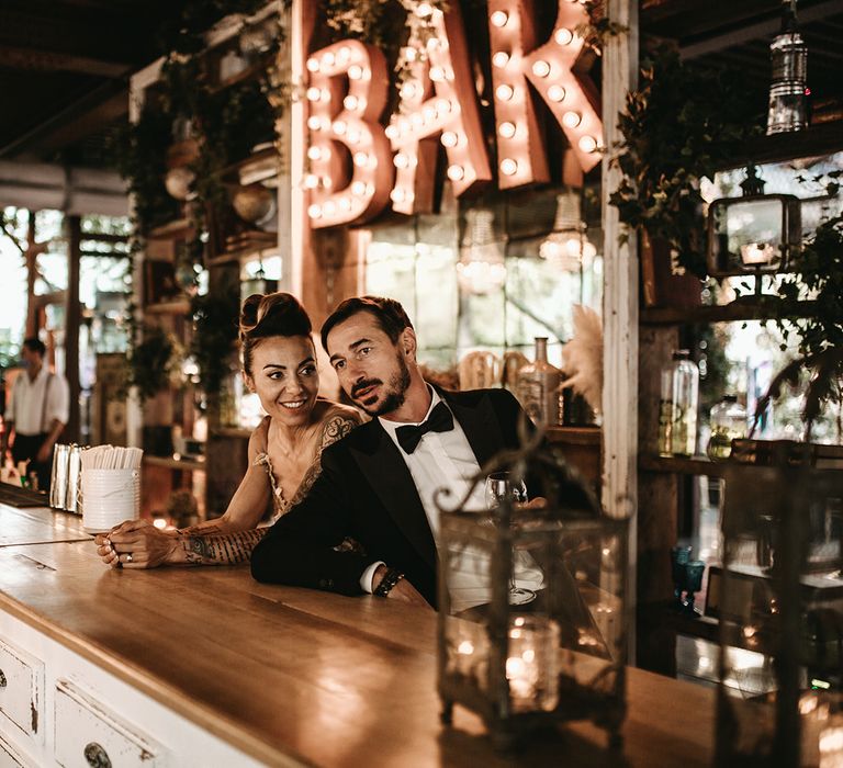 Bride & groom stand behind the bar on their wedding day