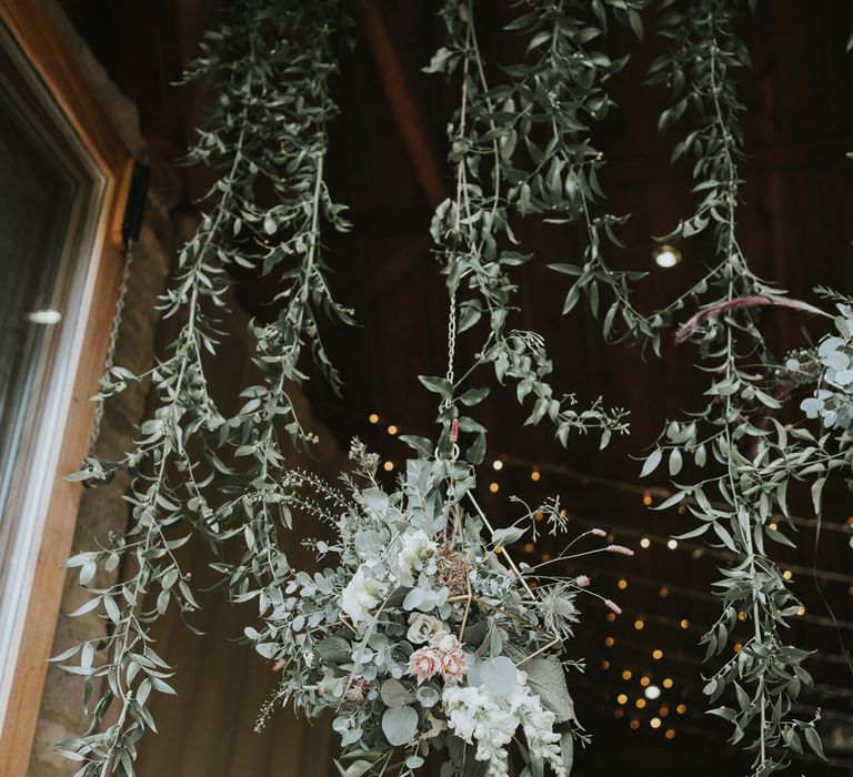 Hanging leaves and hanging flower bomb with pink proteas at Tythe Barn wedding