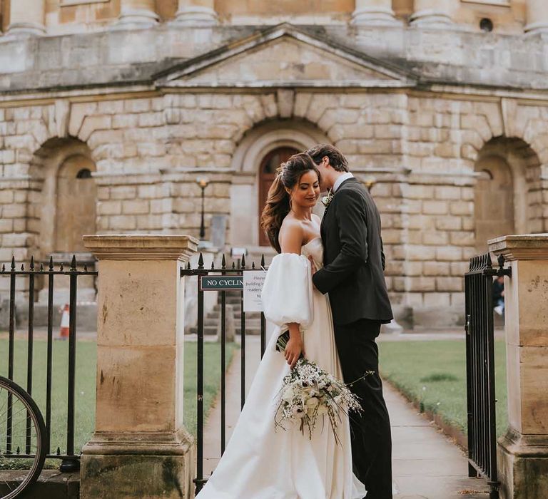 Intimate bride and groom portrait outside Bodleian Library with bride in a strapless wedding dress with full skirt and detachable sleeves