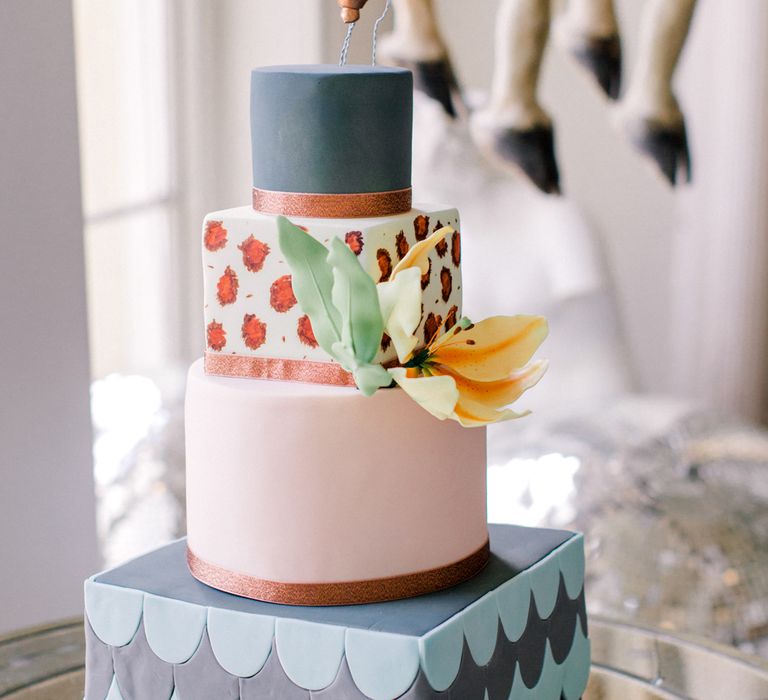 colourful royal iced wedding cake with square and round layers topped with hot air balloon decor 