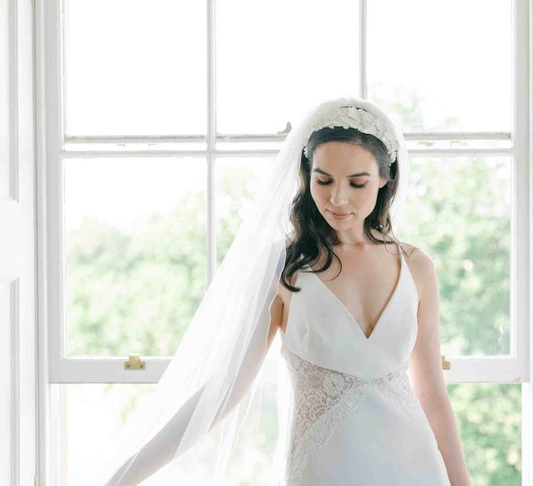 Bride in a slip wedding dress with lace inserts and a long cathedral length veil and appliqué headband 