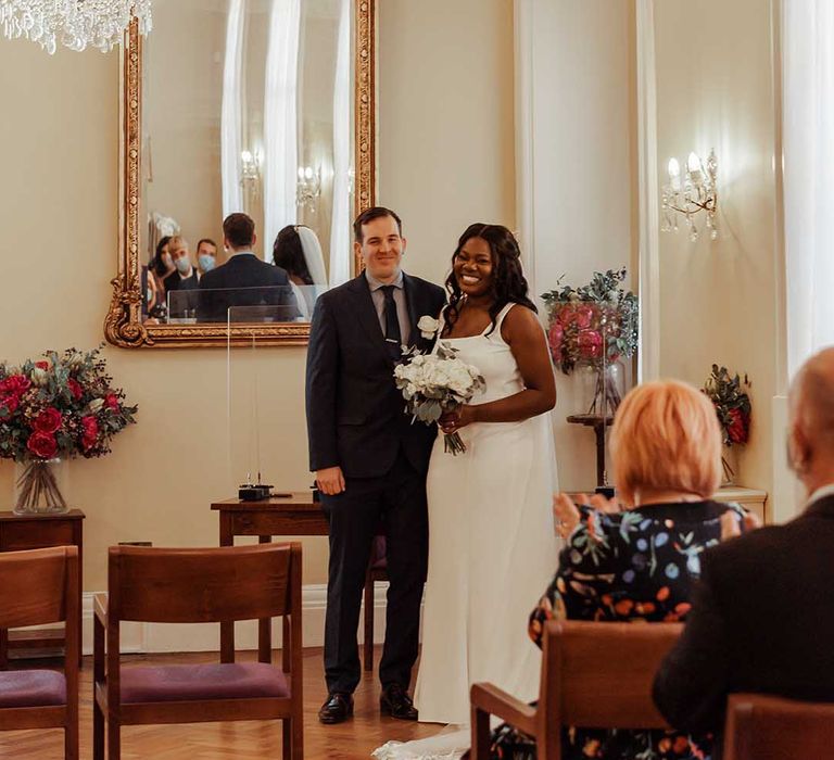 Bride & groom smile as bride holds elegant white floral bouquet