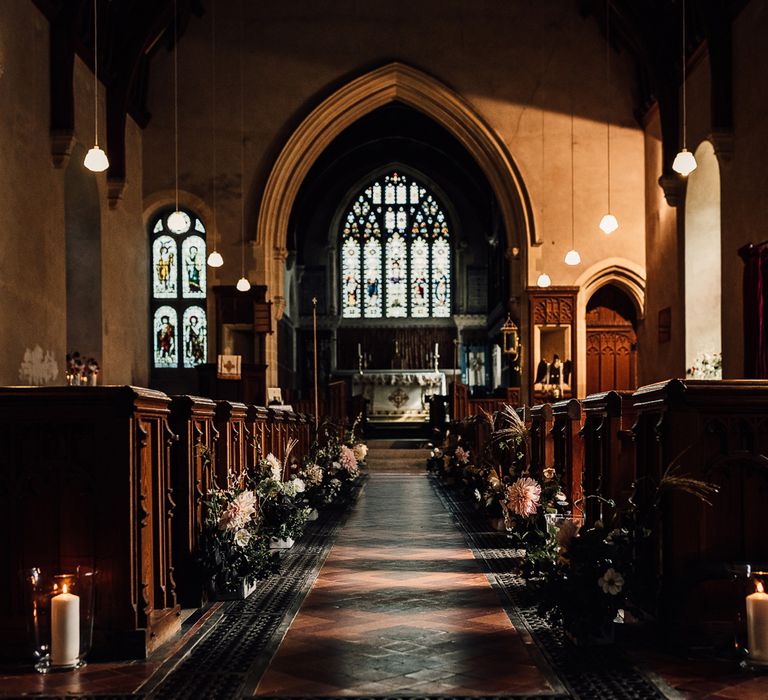 Interior of Cornish church wedding ceremony with florals, candles and hanging lights