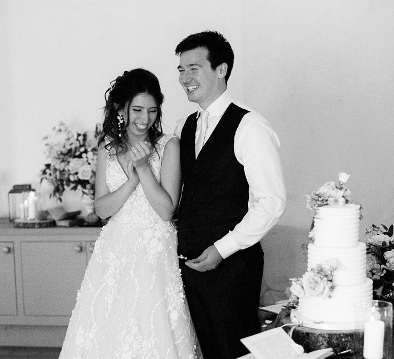 Black & white image of bride & groom on their wedding day before cutting their cake