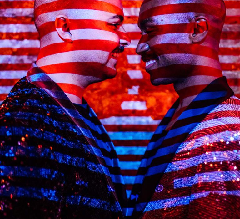 two grooms in sequin jackets with a stripy shadow casting across their face 