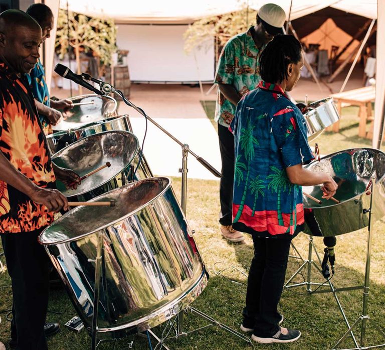 Band in brightly coloured short sleeved shirts plat steel drums for outdoor wedding reception 