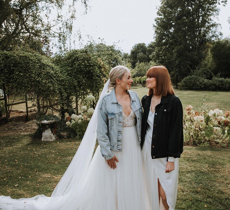 Brides in personalised denim jacket cover ups at The Great Tythe Barn wedding venue