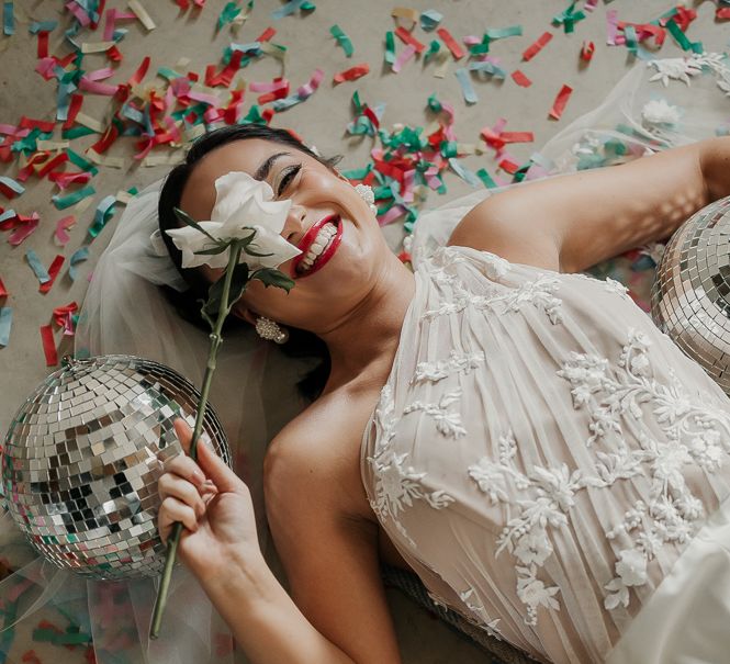 Bride lays on the floor surrounded by confetti and disco balls