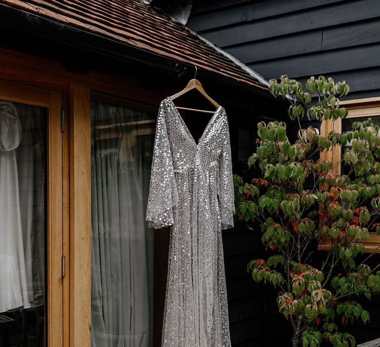 Silver, sequin, Chosen By Kyha wedding dress hanging up 