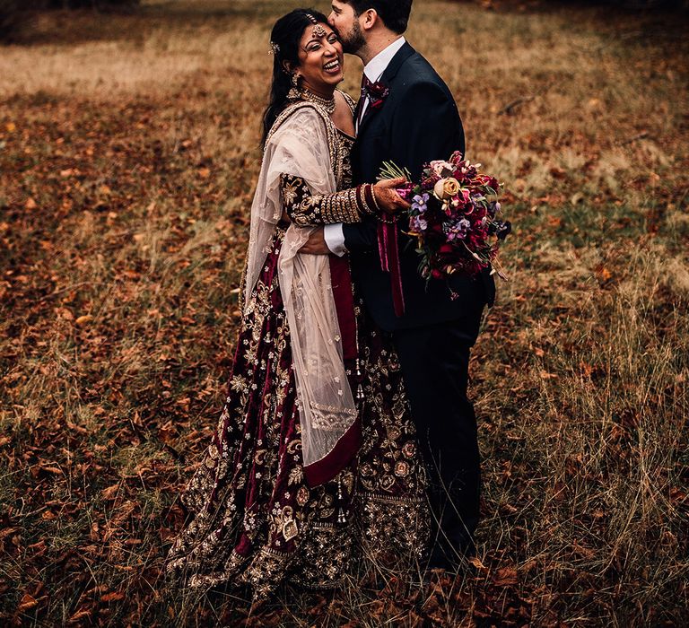 Bride wears Indian Saare wedding dress & holds bouquet of flowers in field with Groom 