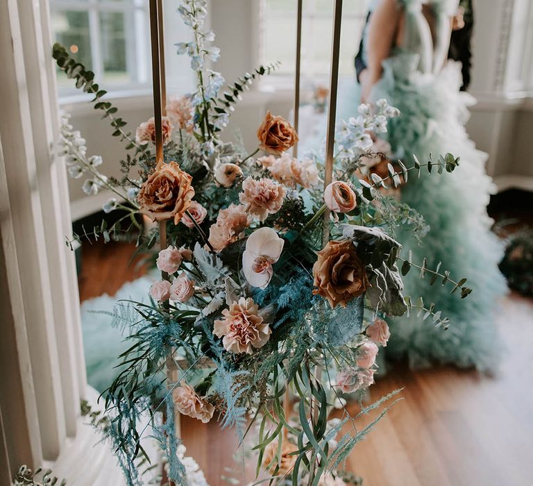 wedding flower arrangement on a metal frame with blush pink and peach orchids, roses, Ranunculus, carnations and foliage 