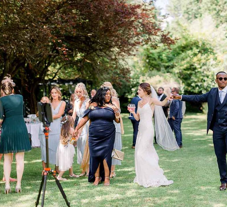 Bride & groom stand outdoors and listen to gospel choir with their wedding guests 