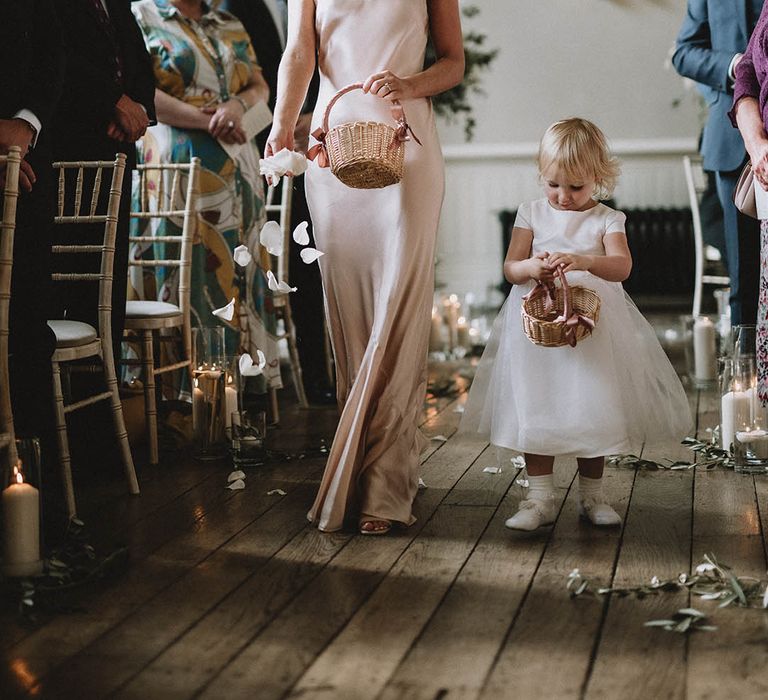 Light pink satin bridesmaid dresses with flower girl lining the aisle with petals