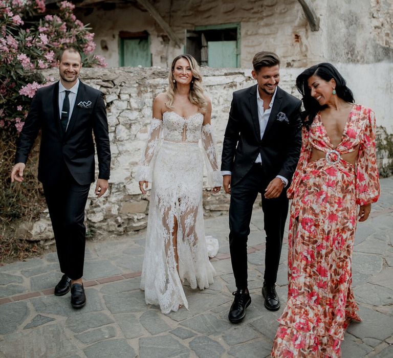 Bride & groom walk with wedding guests outdoors in Greece on their wedding day