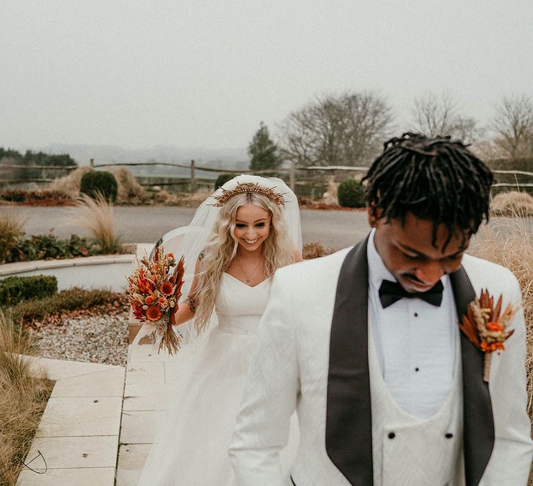 Bride in gold wedding crown approaches groom for first look