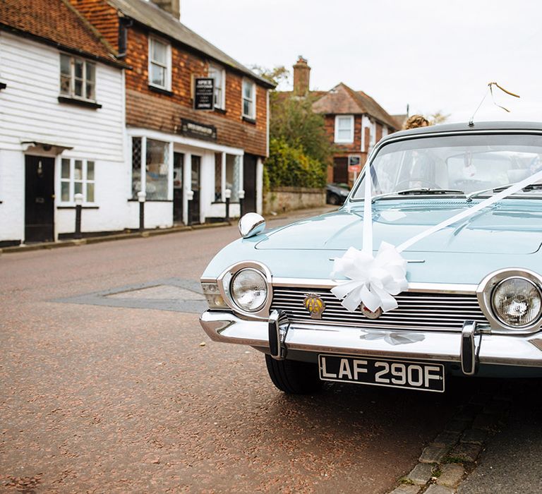 Vintage blue wedding car transportation with white ribbon bows