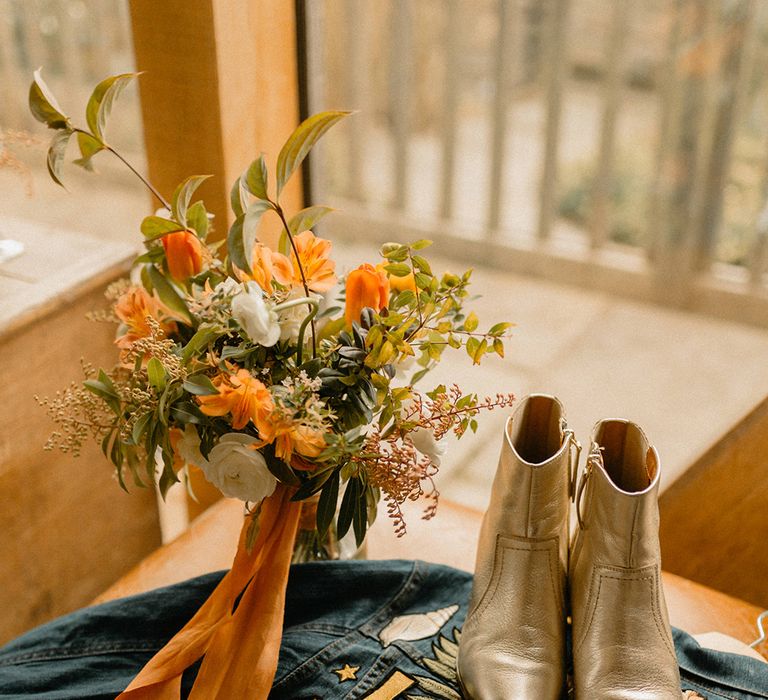 Bride's embroidered denim jacket with gold metallic boots and bouquet 