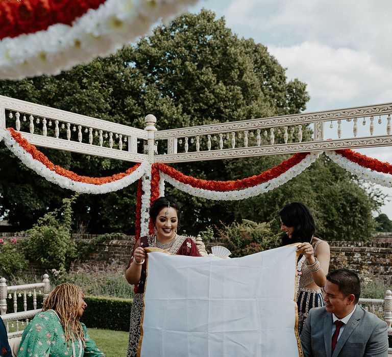 Groom sits beneath mendap as shawl is placed in front of him before being revealed to his bride 