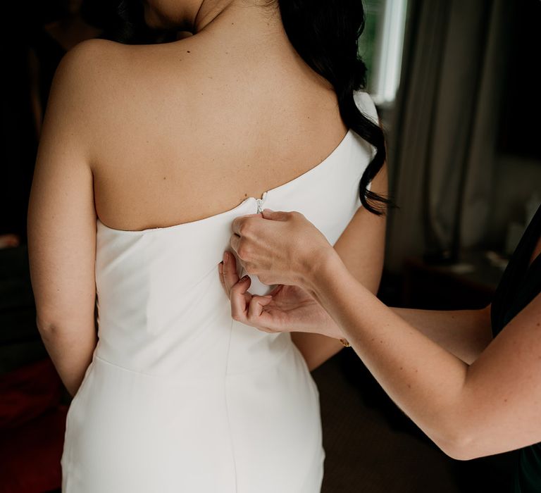 Bride gets zipped up into her one shoulder Madi Lane wedding dress 