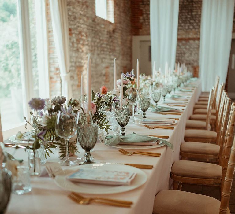 Pretty pastel wedding tablescape with pink taper candles, green napkins and ribbons with a flower print menu card, and pastel flowers