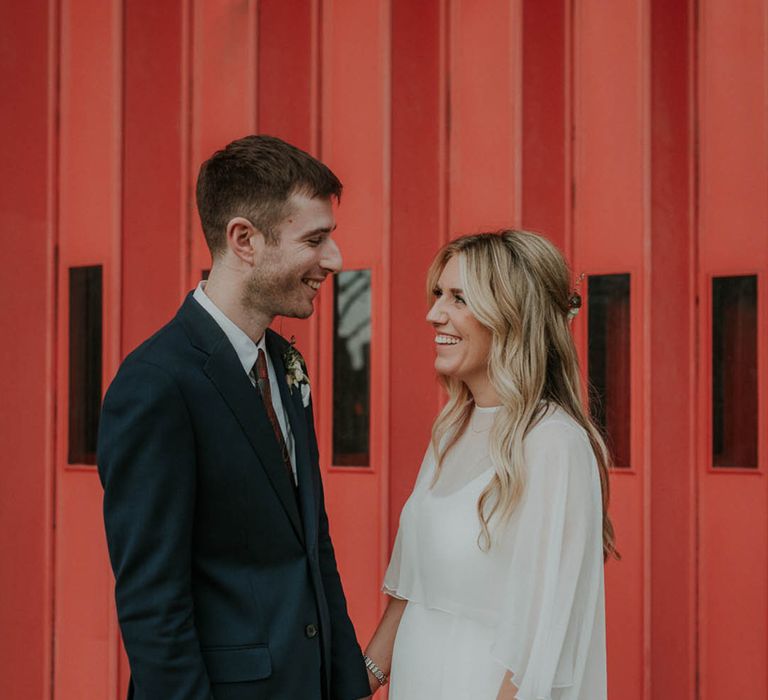 Groom in a blue suit with bride in a simple sheer cape and white wedding dress