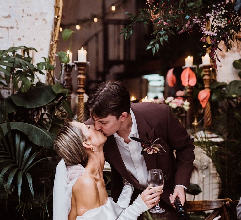 Bride and groom share a kiss as the groom reads out his speech at their wedding reception 