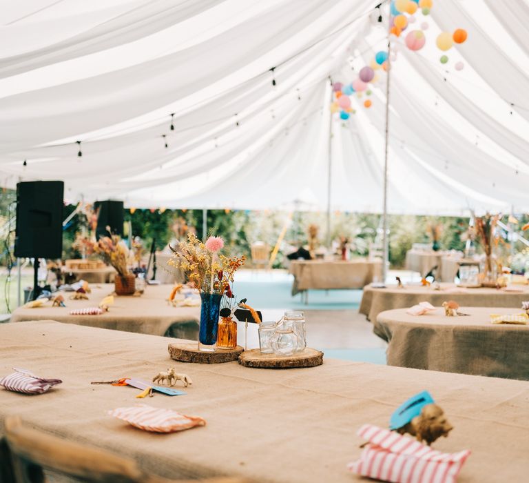 Marquee complete with brightly coloured hanging lanterns and hessian table clothes complete with dried floral centrepieces on wooden slabs