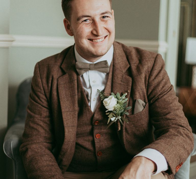 Groom in a brown checkered suit with a bow tie and beige trousers for classic country house wedding 