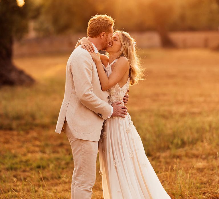 Bride and groom kiss during golden hour for their outdoor destination wedding in summer 