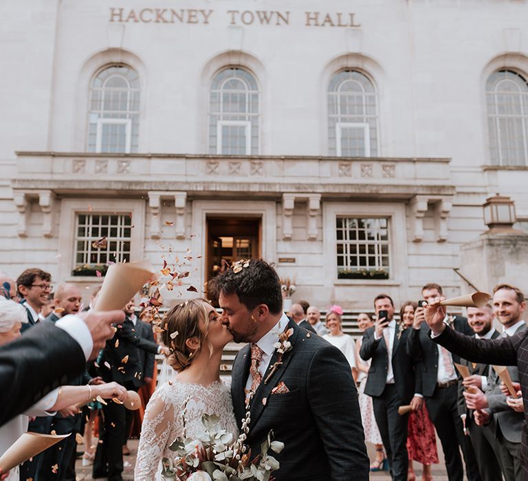 Bride & groom kiss outside Hackney Town Hall as colourful petal confetti is thrown around them