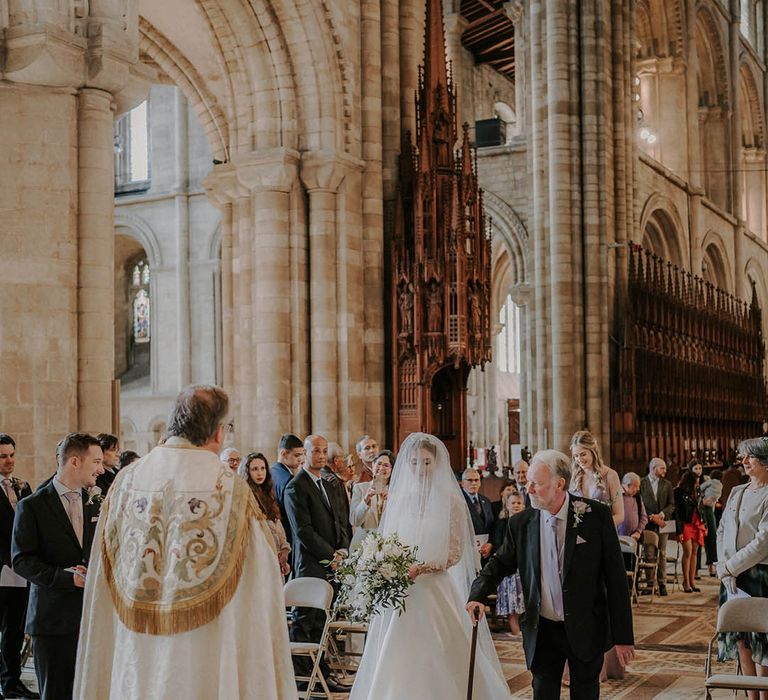 Father of the bride walks the bride down the aisle for a traditional classic wedding 